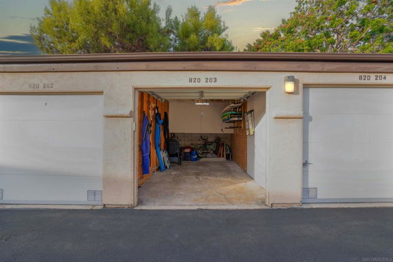 Outdoor parking area with a partially open garage showing various stored items.