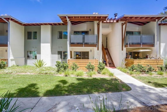Front view of a two-story apartment building with balconies and wooden accents.