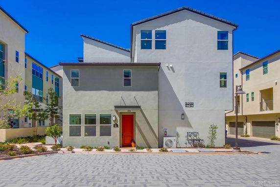 Front view of a multi-story residential building with a red door.