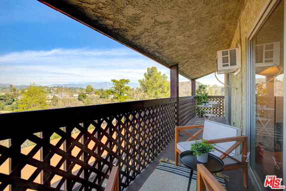 Outdoor balcony with seating area and view of surrounding landscape.