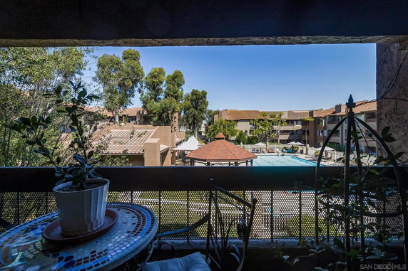 View from a balcony showing a swimming pool and surrounding residential buildings.