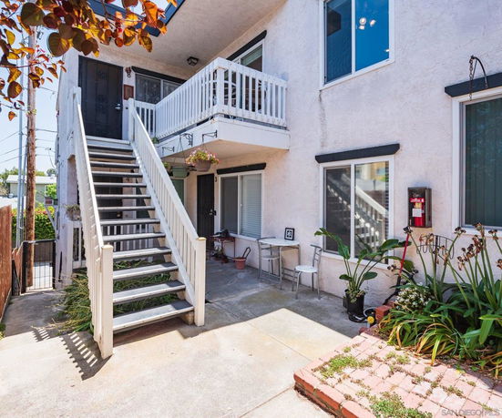 Front view of a two-story residential building with an external staircase leading to the upper floor.