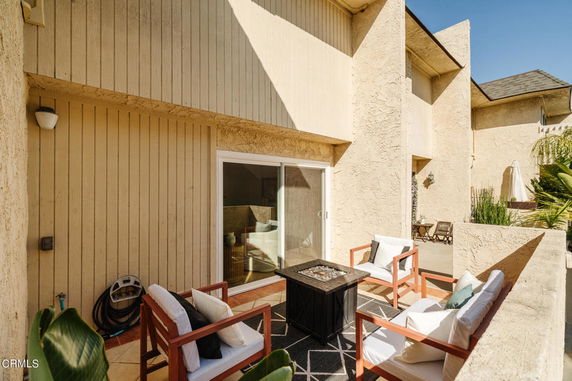 Outdoor patio view of a beige building with a seating area and sliding glass doors.