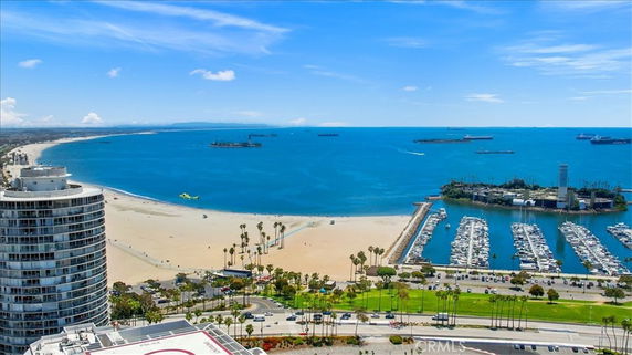 Panoramic view of a beach and marina with a high-rise building in the foreground.