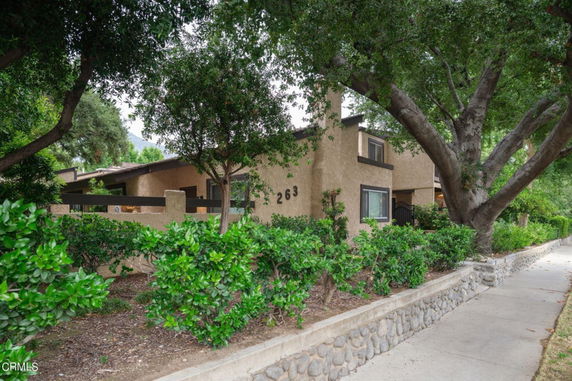 Front view of a two-story house with a side entrance and surrounding trees.