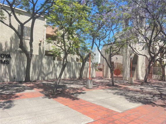 Front view of a multi-story building with trees and a gated entrance.