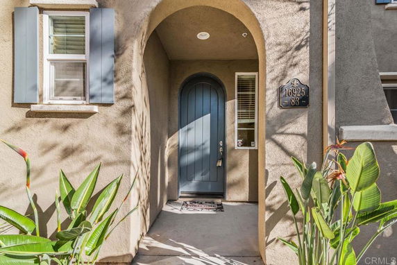 Front view of a house entrance with an arched doorway and blue shutters.
