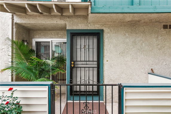 Front view of a house entrance with a metal door and small porch area.