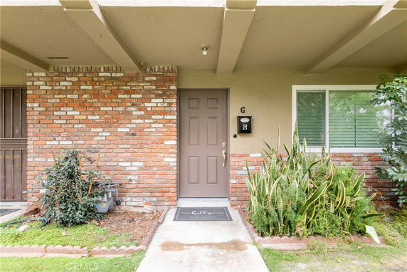 Front view of a house with a brick wall and a single door entrance.
