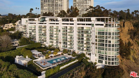 Front view of a modern multi-story building with large windows and a rooftop terrace.