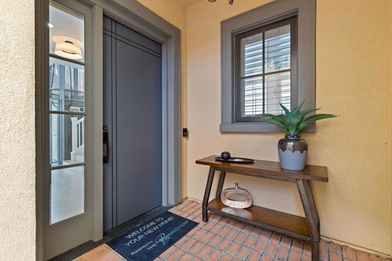 Front entrance of a house with a light grey door and small window next to it.