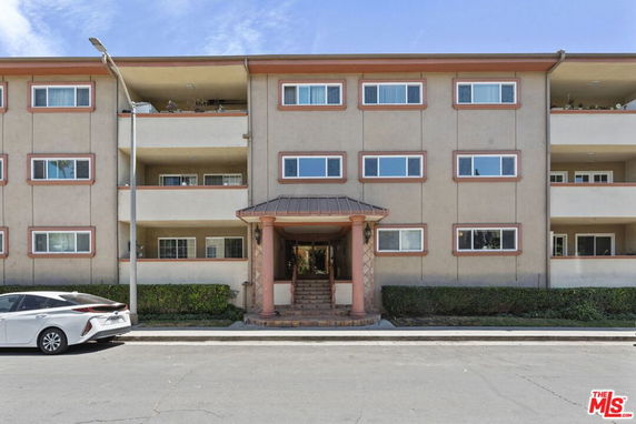 Front view of a multi-story residential building with balconies and a central entrance.