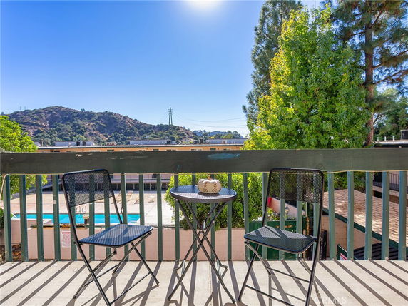 Balcony view with two chairs and a table overlooking distant hills and trees.