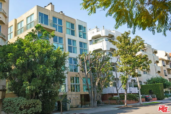Front view of a multi-story apartment building with large windows and balconies.