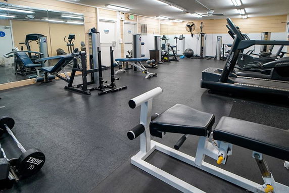 Indoor gym area with various fitness equipment, including treadmills and weight machines.