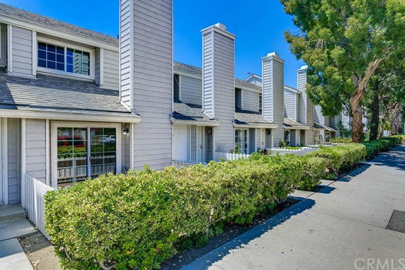 Front view of a row of townhouses with chimneys and front porches.