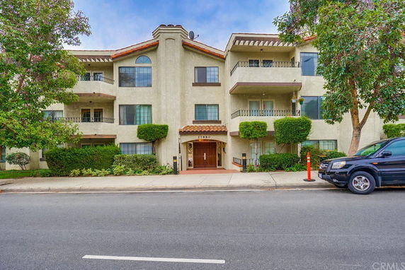 Front view of a three-story residential building with balconies and a central entrance.