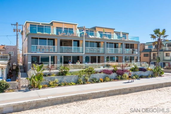 Front view of a multi-story beachside apartment building with large glass balconies.
