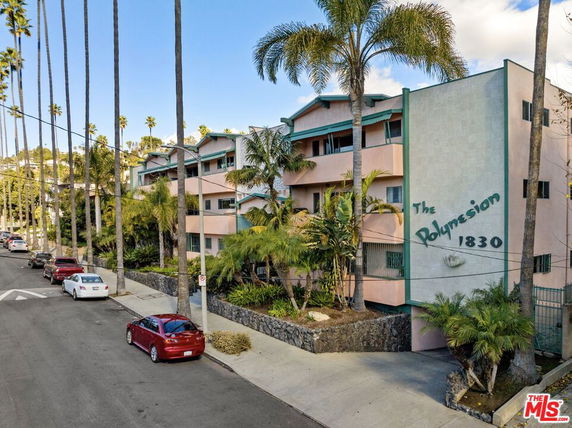 Front view of a multi-story residential building with tropical landscaping.