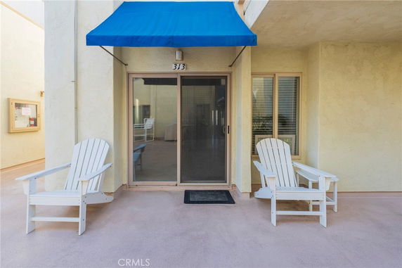 Front view of an outdoor patio area with chairs and a sliding glass door.