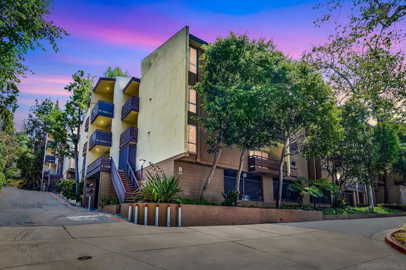 Front view of a multi-story apartment building with balconies and exterior stairs.