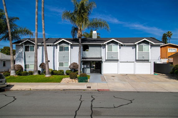 Front view of a two-story house with a double garage and palm trees in front.