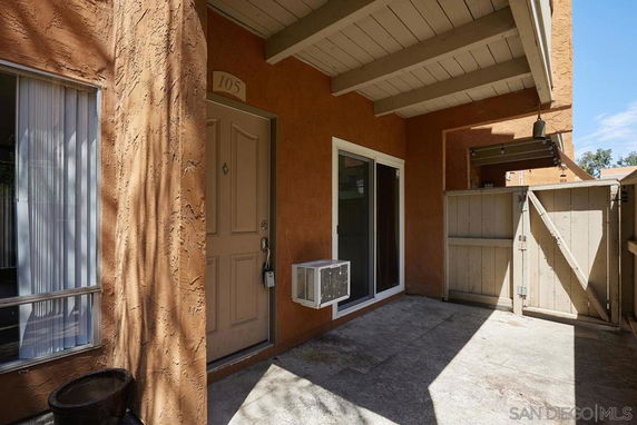 Front view of a building entrance with an air conditioning unit and gate.