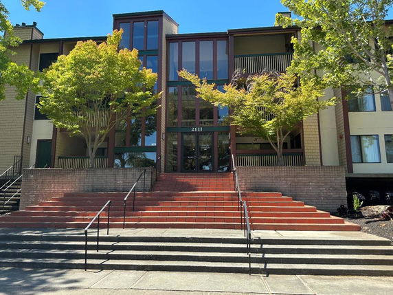 Front view of a multi-story building with large windows and a central staircase.