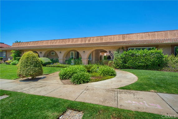 Front view of a single-story house with arched entryways and a tiled roof.