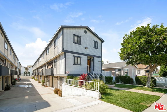Front view of a multi-story residential building with balconies and a garage area underneath.