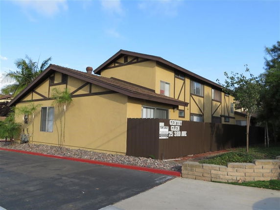 Front view of a multi-story house with a brown roof and beige walls.