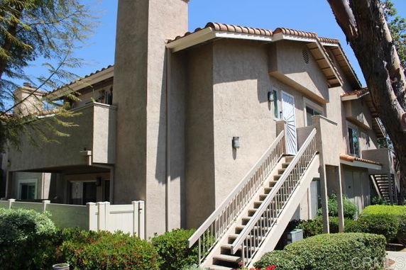 Front view of a two-story house with exterior stairs and a chimney.