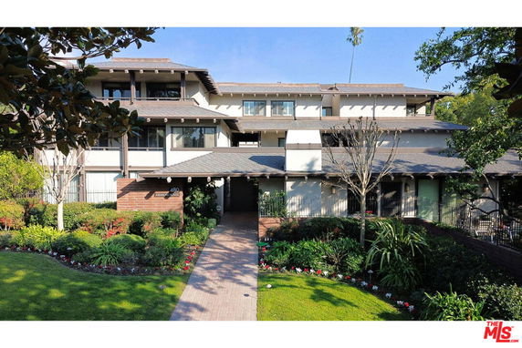 Front view of a multi-story residential building with a landscaped entrance.