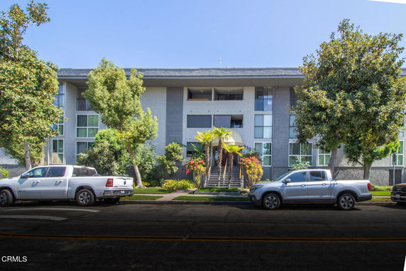 Front view of a multi-story residential building with large windows and a central staircase entrance.