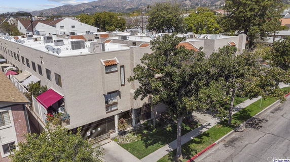 Front view of a multi-story building with a flat roof and balconies.