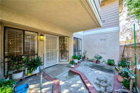 Front view of a residential building with a covered entrance patio and potted plants.
