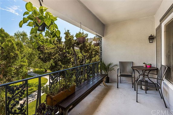 Outdoor balcony with seating and view of trees and garden.