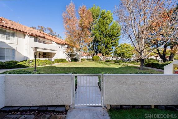 View from behind a gate of a building with trees and grass area.