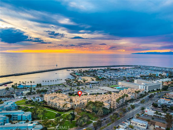 Panoramic view of coastal buildings and marina at sunset.