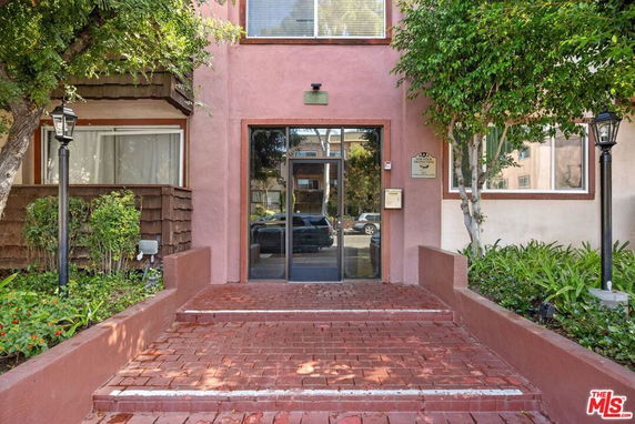 Front view of a residential building entrance with steps leading up to a glass door.