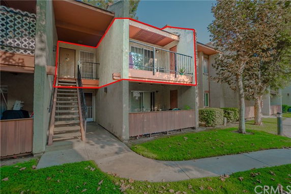 Front view of a two-story apartment building with balconies and an exterior staircase.