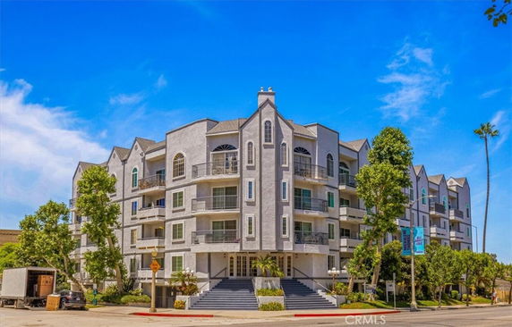 Front view of a multi-story residential building with balconies and decorative architecture.