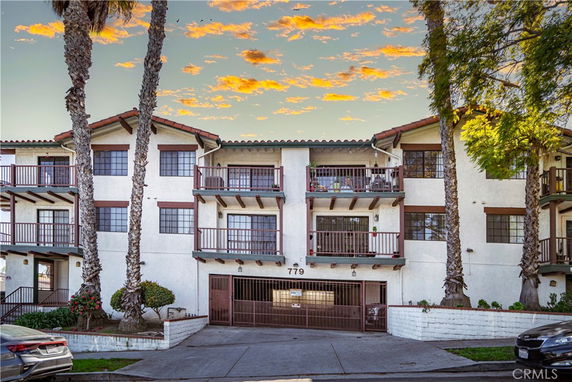 Front view of a multi-story building with balconies and a gated entrance.
