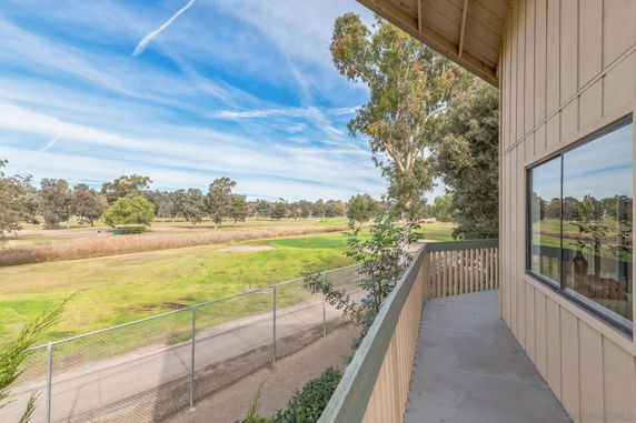 View from a building's balcony overlooking a grassy area and trees.