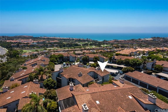 Panoramic view of residential area with tile-roofed houses and visible coastline in the background.