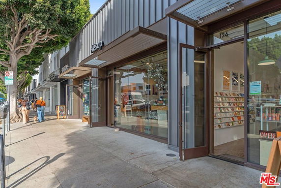 Front view of a row of retail storefronts with large glass windows and metal awnings.