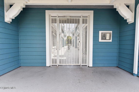 Entrance of a house with a decorative security screen door and blue exterior siding.