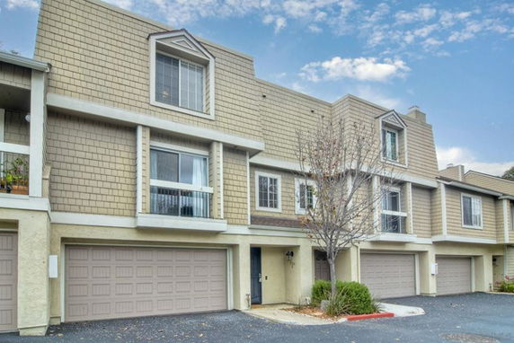 Front view of a townhouse with multiple garages and a tree in front.
