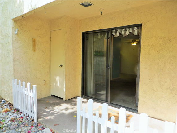 Exterior view of a house with a sliding glass door and a small white fence.
