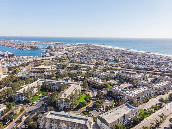 Aerial panoramic view of a coastal city with numerous buildings and the ocean in the background.